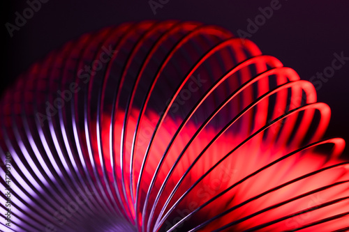 Foto Closeup of coiled metal spring with sufficiently high strength and elastic properties in neon light over dark background
