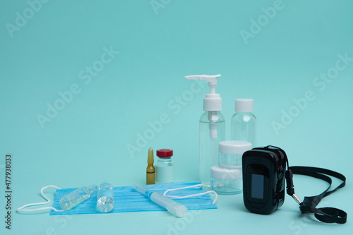 Pulse oximeter, mask, coronavirus vaccine and syringe on a blue background. Diagnosis of Covid 19.