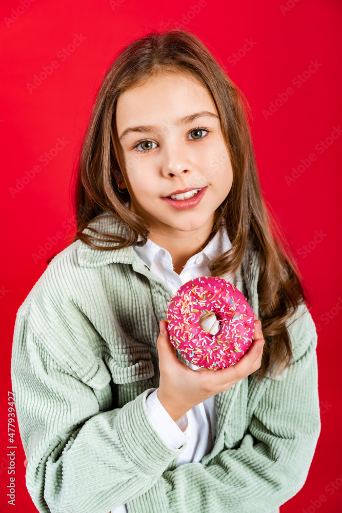 portrait of a beautiful girl in a green denim jacket and white shirt with loose hair. teenager with donut. on a red background portrait of a beautiful girl in a green denim jacket and white shirt with loose hair. teenager with donut. on a red background