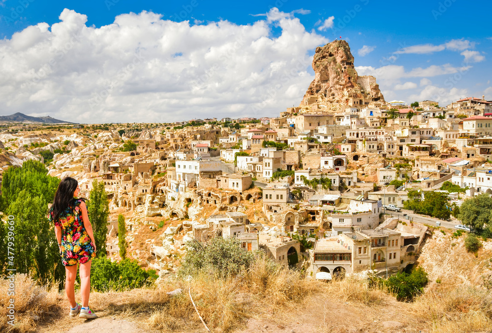 Caucasian young woman tourist on viewpoint stand and watch Ostahisar castle landmark in Cappadocia. Travel holidays in Turkey