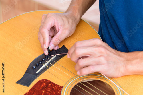 The musician replace the new guitar strings for his guitar photo