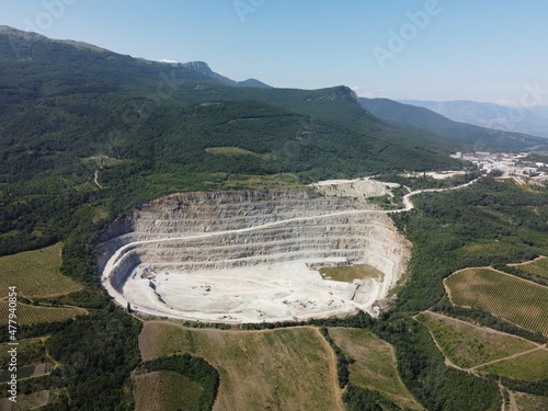 Aerial view industrial of opencast mining quarry with lots of machinery at work - crushed stone and building materials for the constractions industry. Oval mining industrial crater, acid mine drainage photo