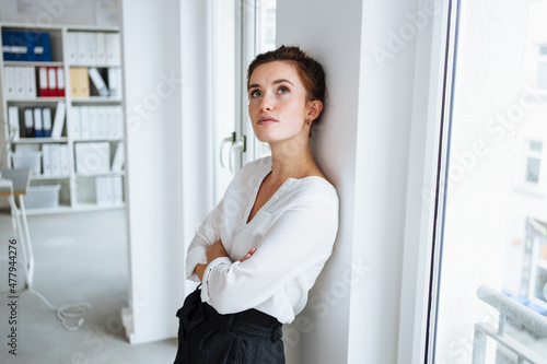 Foto Serious young businesswoman standing deep in thought