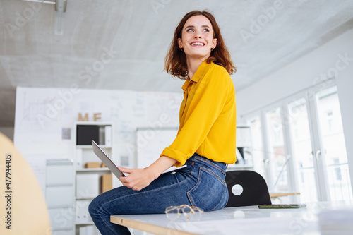 Happy young business employee sitting on table photo