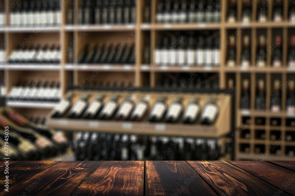 Wine wooden table background. Blurred wine shop with bottles on the counter. Wine wooden table background. Blurred wine shop with bottles on the counter.