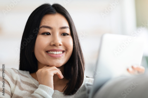 Closeup Shot Of Young Smiling Korean Woman Using Digital Tablet At Home