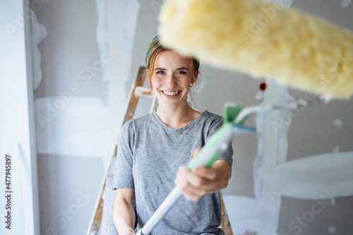 Fotografie Happy smiling young woman brandishing a paint roller