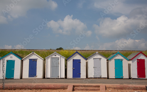 Beautiful colourful beach huts by the beach with blue sky and clouds in the background