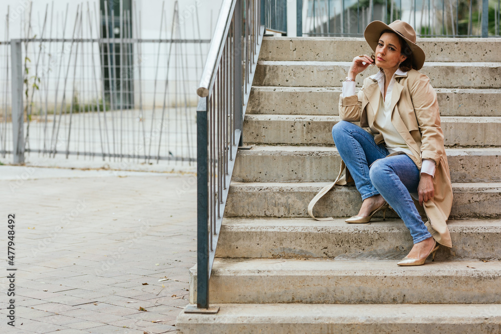 Thoughtful woman thinking about something while sitting on the stairs in the street. Thoughtful woman thinking about something while sitting on the stairs in the street.