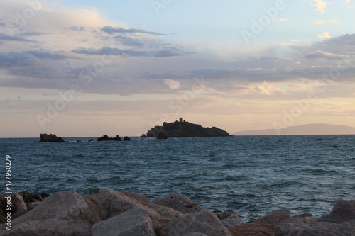 Tramonto con vista delle onde e di un isola rocciosa. Punta ala