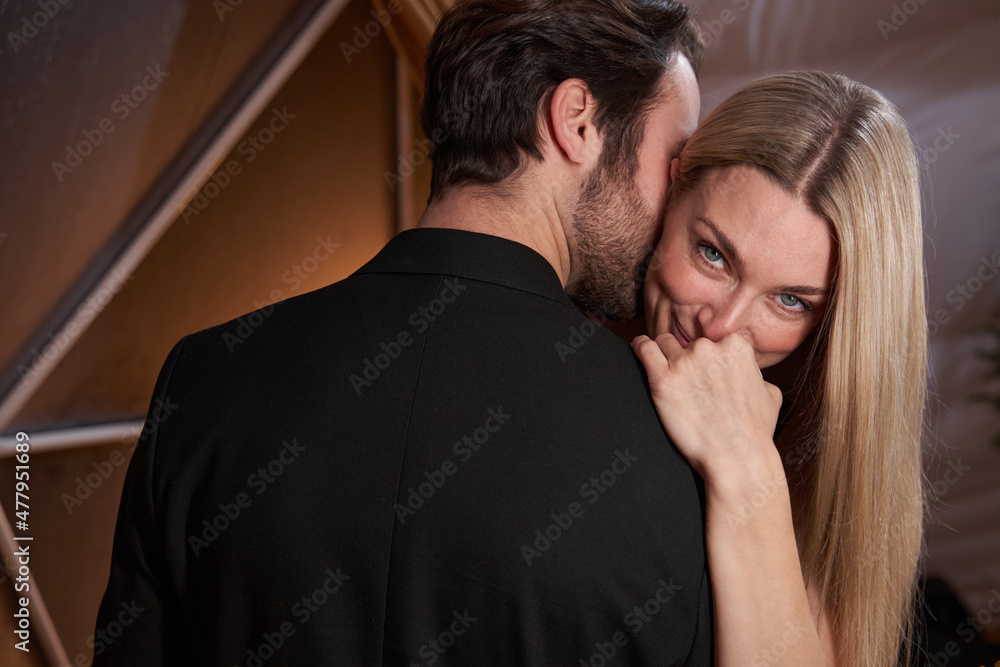 Woman shyly smiling to camera during dance with man Woman shyly smiling to camera during dance with man