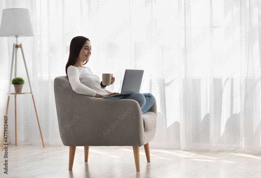 Businesswoman work on laptop computer at home holding coffee cup in hand Businesswoman work on laptop computer at home holding coffee cup in hand