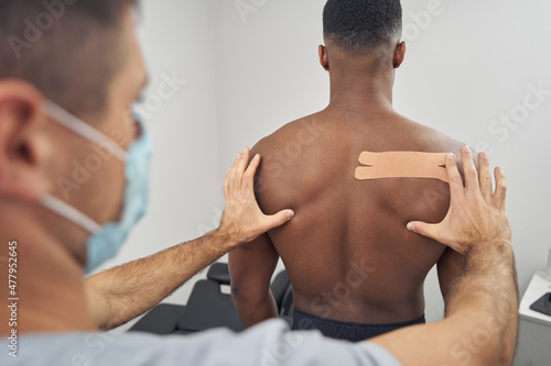Doctor using kinesiology taping technique during physiotherapy session