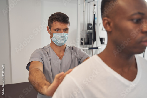 Experienced doctor examining spine of young man