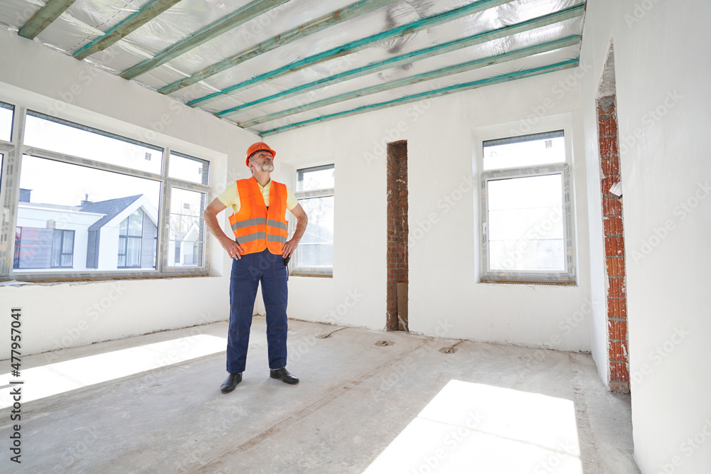 Builder inspecting empty room in unfinished building
