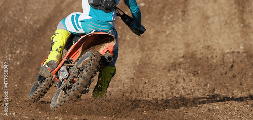 Racer boy on motorcycle participates in motocross race, active extreme sport, flying debris from a motocross in dirt track photo
