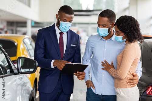 Salesperson In Medical Mask Consulting Black Spouses In Dealership Center
