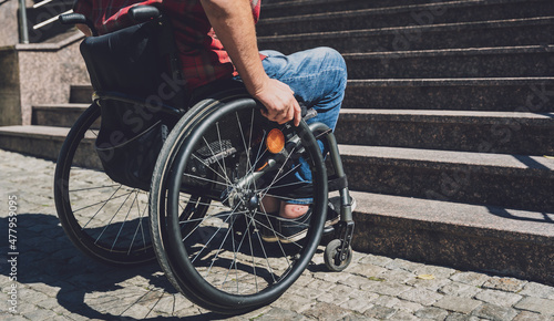 Young man with a physical disability who uses wheelchair in front of the stairs