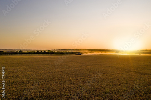 Combine harvester on the field at sunset. Aerial view 