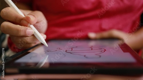 Close-up hand using digital pen drawing on computer tablet