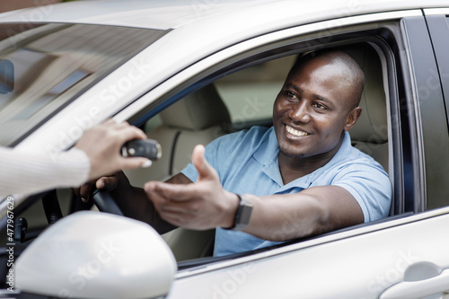 Black man taking key from car, renting auto for trip