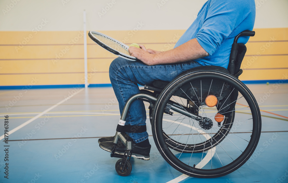 Obraz premium Adult man with a physical disability who uses wheelchair playing tennis on indoor tennis court
