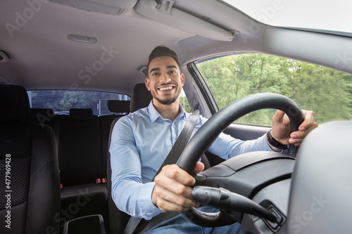 Smiling arab guy driving his car, shot from dashboard