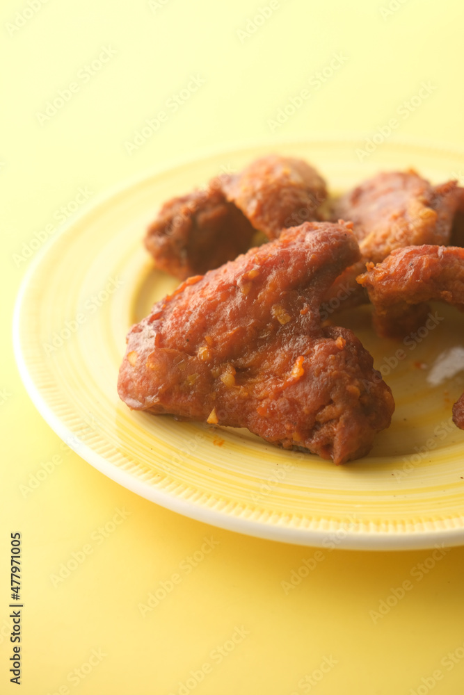 chicken wings in a plate on yellow background 