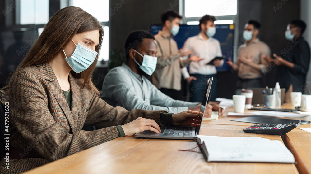 Colleagues working on a project wearing face masks using technology Colleagues working on a project wearing face masks using technology