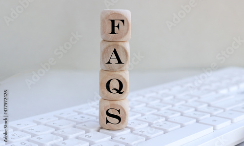wooden cube at having with text FAQS on Keyboard.