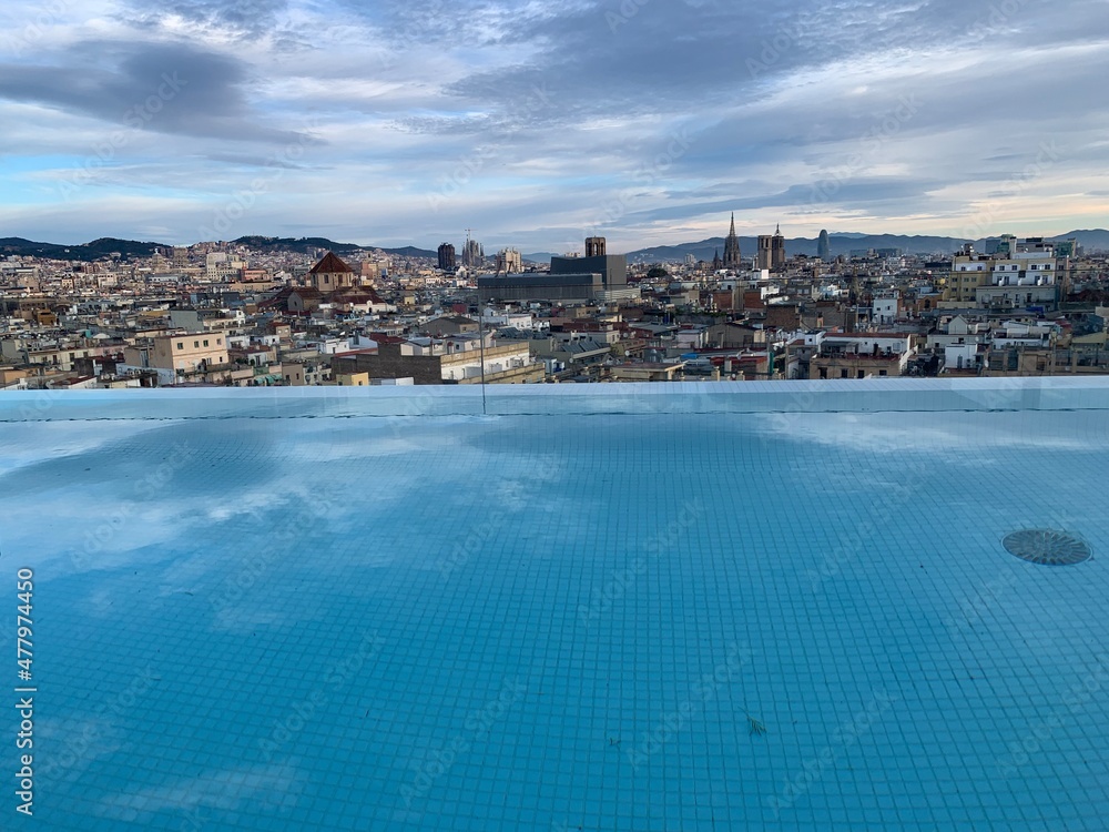 View of Barcelona city skyline from a rooftop pool. Sagrada de Familia and other famous sightseeing objects in the background. Aerial, panoramic, scenic view of Barcelona. Catalonia, Spain