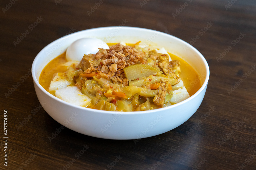 A plate of Indonesian food with vegetable curry, boiled egg and lontong rice A plate of Indonesian food with vegetable curry, boiled egg and lontong rice