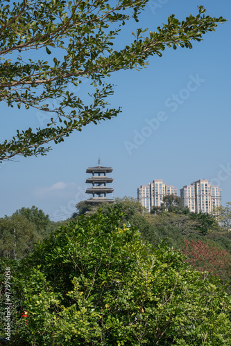 A tower under the blue sky and green trees