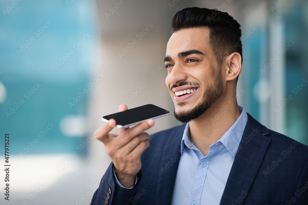 Ecstatic middle-eastern man entrepreneur recording audio message on smartphone Ecstatic middle-eastern man entrepreneur recording audio message on smartphone