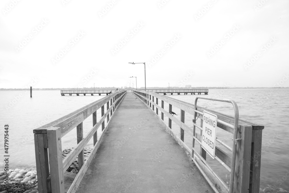 Black and White view fishing pier with gate and sign stretching out Clear Lake near Seabrook, Greater Houston, Texas, USA