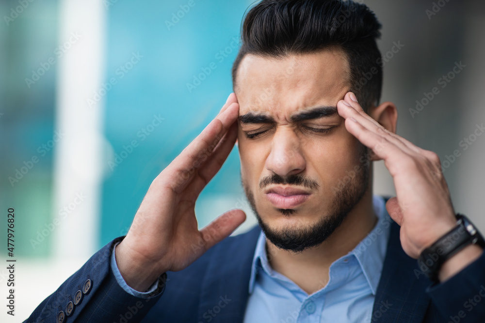 Stressed young arab businessman suffering from headache Stressed young arab businessman suffering from headache