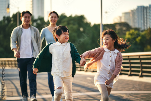 Photography asian family with two children taking a walk in city park