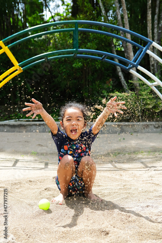 Asian kid playing with the beach sand and showing happy expression © KrishnaTedjo