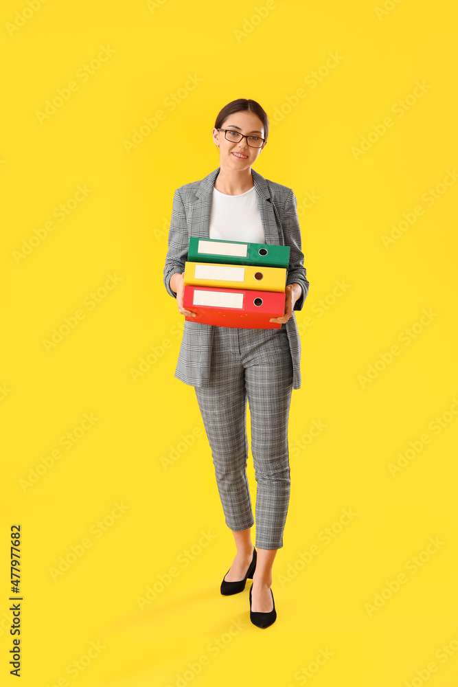 Teenage girl holding folders on yellow background Teenage girl holding folders on yellow background