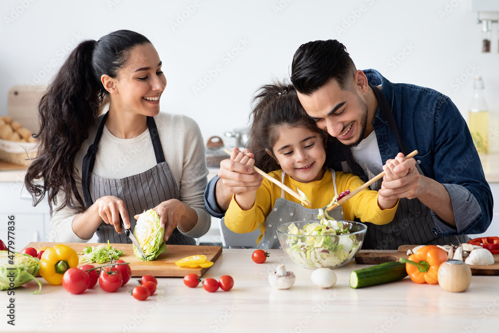 Portrait Of Cheerful Young Arab Family With Cute Little Daughter Cooking Together