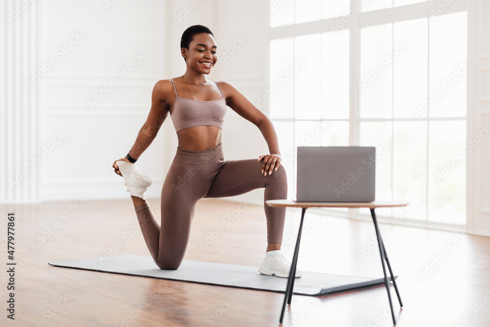 Obraz premium Smiling African Woman In Sportswear Doing Legs Quad Stretching Exercise