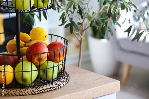 Stand with healthy fruits on counter in modern kitchen, closeup photo