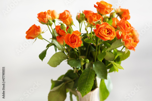 Vase with beautiful orange roses in room, closeup