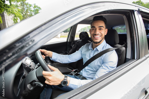 Handsome arab businessman driving car, shot from outside