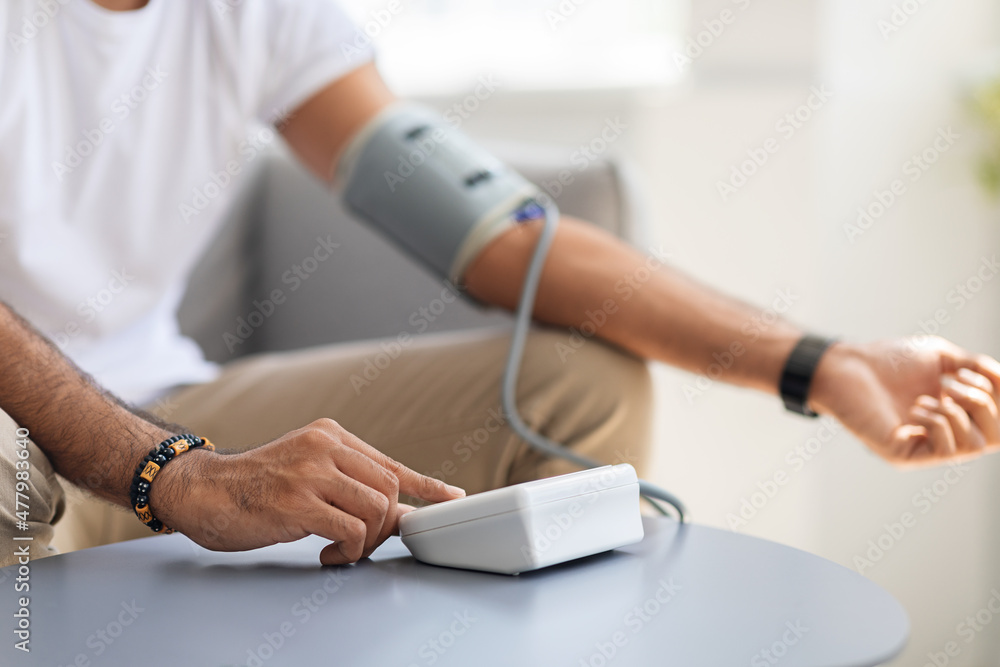 Unrecognizable man using modern tonometer at home Unrecognizable man using modern tonometer at home