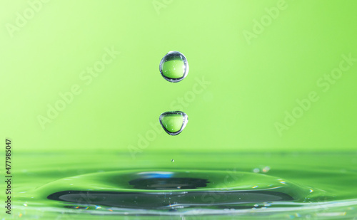 Water drop falling and impacting body of water.