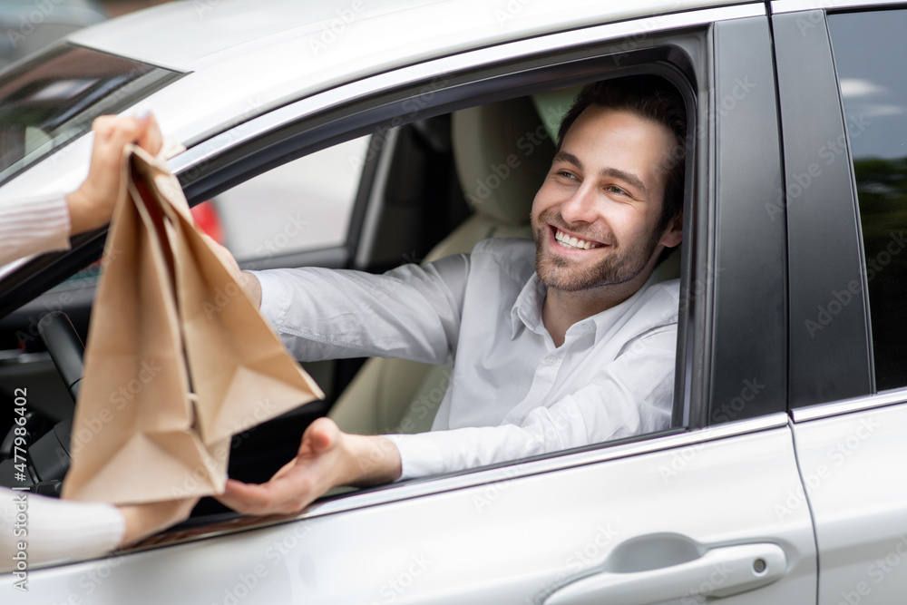 Food delivery courier gives paper bags to man in car. Safety food delivered