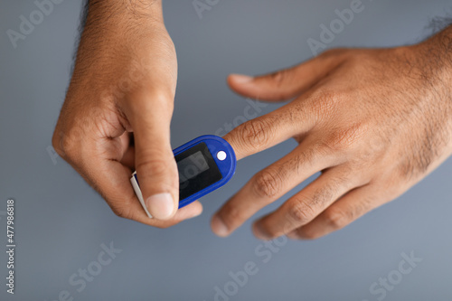 Unrecognizable man using pulse oximeter, grey background