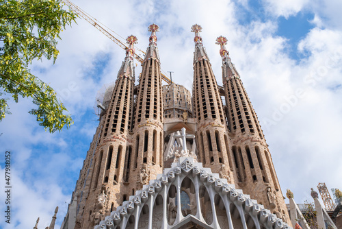 Low angle view of The Basílica de la Sagrada Família also known as the Sagrada Familia in Barcelona city centre. Cloudy sky and crane on a background.
