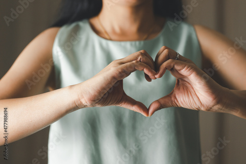 Close up of woman making heart shape for Valentines day, Mothers day and Breast Cancer Awareness month for Healthcare of International Women day